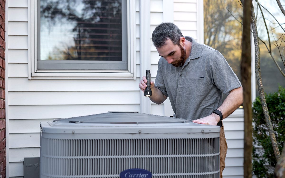 AC technician checking refrigerant pressure during doorstep service